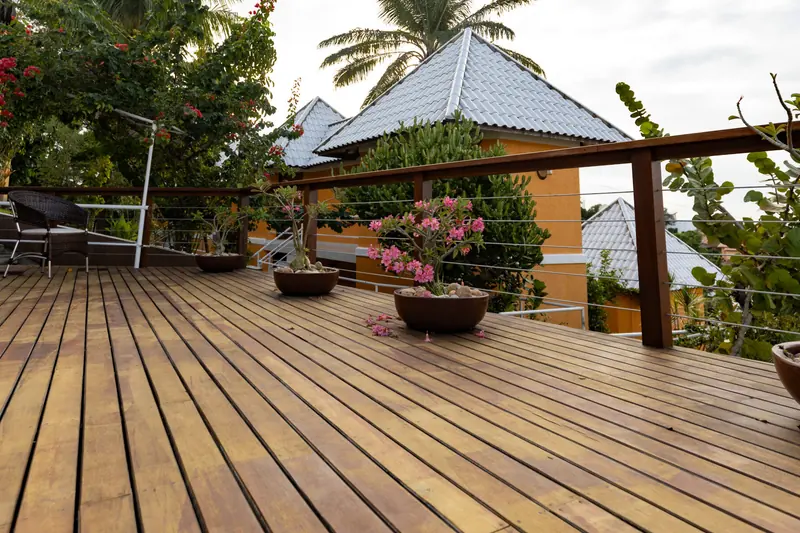 Deck de madeira do hotel com coqueiros e telhados brancos