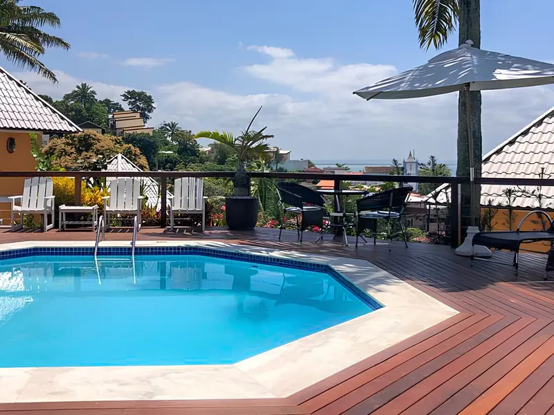 Piscina do hotel com deck, guarda-sóis e vista para a vila