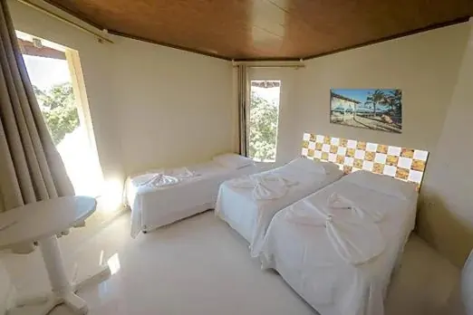 Suíte Superior com camas arrumadas e janela com luz natural