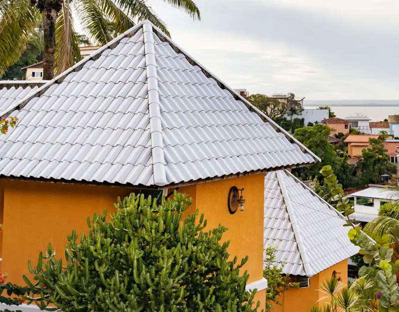Prédio amarelo do hotel entre coqueiros, com a vila e o mar ao fundo
